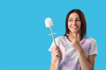 Beautiful woman pointing at toilet brush on blue background