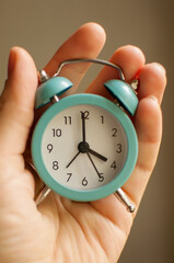 a small blue alarm clock showing 4 hours of time in your hand