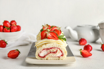 Plate with delicious strawberry roll cake on light background