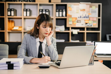 Asian female university student concentrating on her online classroom with tablet and laptop .