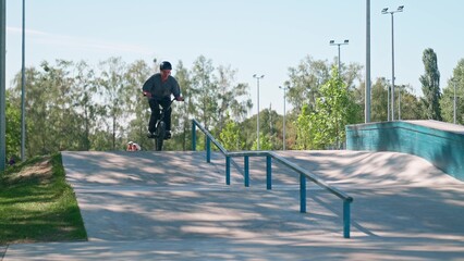 A professional cyclist rides and performs tricks on bmx. Beautiful stunts and bike jumps in the park on a concrete platform with obstacles. BMX.