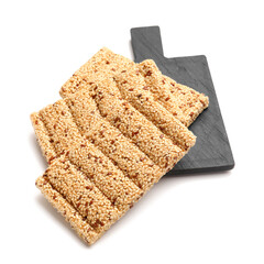 Board with tasty sesame kozinaki on white background
