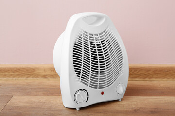 Electric fan heater near pink wall