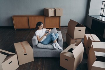 Woman using phone, purchases furniture, chooses relocation service to move packed things to new home