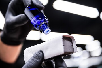 employee of the car detailing studio applies a ceramic coating to a special applicator to protect...