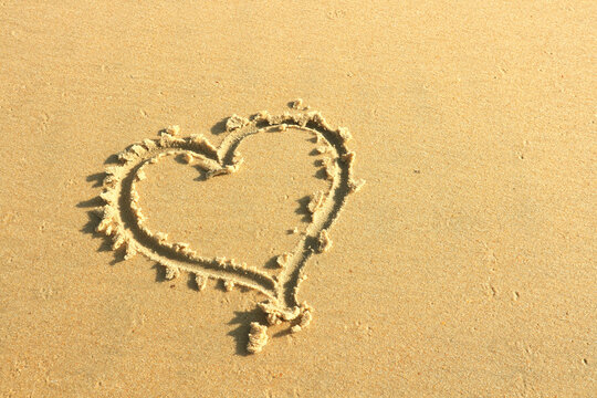 A heart is painted on the sand on the beach - a symbol of love for Valentine's Day. Concept - a trip to the sea and beach holidays as a gift for Valentine's Day.