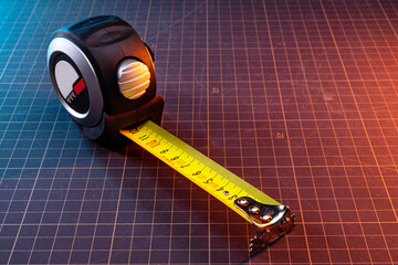 Construction tape measure on the table in the workshop. Analog measuring tool