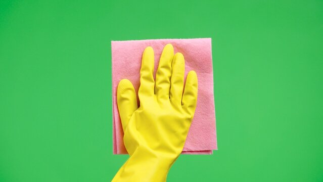 Woman hand in yellow rubber gloves wipes window glass with dry pink rag. Housewife does housework. Cleaning transparent glass from dust. Hygiene, household, cleanup. Green screen chroma key. Close up.