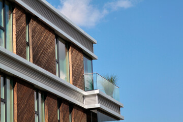 A modern building with glass balcony with a green flower. Selective focus