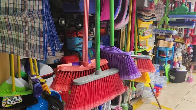 Video of an open air market in Lima selling brooms and mops and other cleaning supplies. Camera tilts up and many different colored brooms can be seen hanging. Recorded in Lima, Peru in 4k quality.