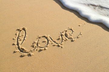 The word love is written in the sand on the beach - a symbol of love for Valentine's Day. The concept is a trip to the sea and beach holidays as a gift for Valentine's Day.