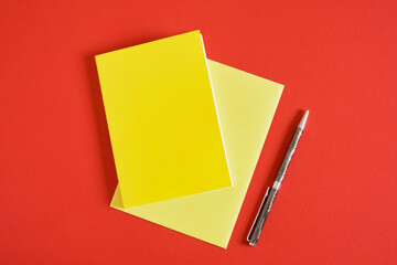 Design concept - Top view of yellow notebook and pen collection isolated on red background for mockup