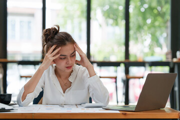 Stressed Asian business woman worry with many document on desk at office