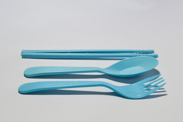 Plastic cutlery set isolated on a white background, consisting of a spoon, fork, and chopsticks.