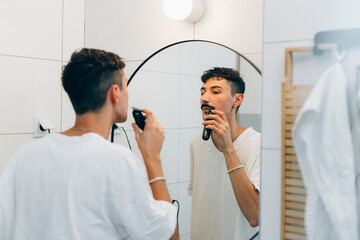 young adult man trimming hos mustaches in bathroom