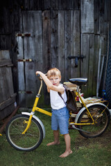 Chłopiec z rowerem i plecakiem idzie zabłąkany do nowej szkoły
