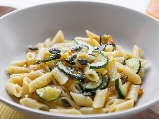 Dish of penne pasta with zucchini, seeds and parmisan. close up. Carbo portion ready for eat. Italian food, healthy vegetarian food. vegetable recipe for diet