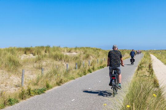 People cycling along dunes at Dutch coast of North Holland between Schoorl and Petten in The Netherlands