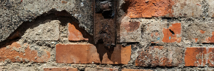 Old wall with rusty steel beam and crumbling plaster. Panoramic image