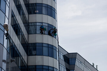 Fototapeta na wymiar Industrial mountaineering workers hangs over facade building