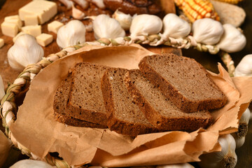 still life of food in a rural style on a dark wood background, rye bread and garlic, concept of fresh vegetables and healthy food