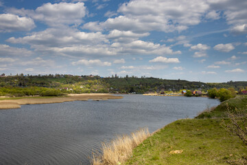 Rural spring landscape, clouds over the horizon. Sunlight through the clouds illuminates the young greenery of bushes and trees.