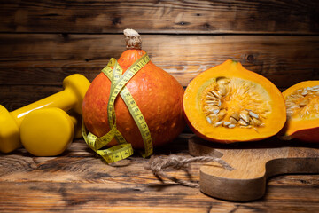 Hokkaido pumpkins with tape measure or measuring tape and dumbbells. Healthy fitness lifestyle...