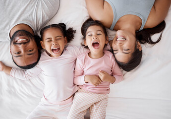 Family happy, crazy children and above bed with parents in the morning, funny face in the house and comic portrait together in home. Top view of mother and dad smile with girl kids in bedroom