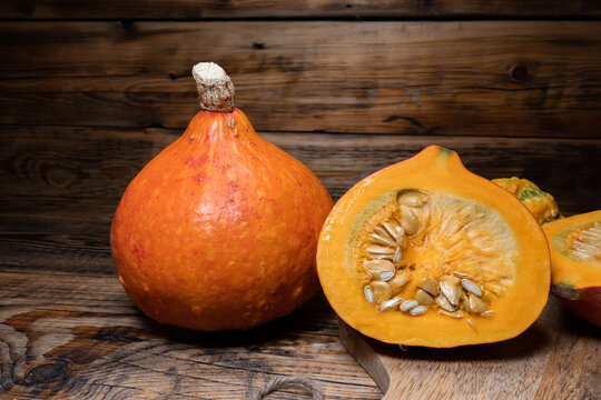 Hokkaido pumpkins on wooden background. Red kuri squash autumn fall rustic composition for Halloween or Thanksgiving.