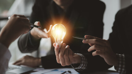 Businessman holds a glowing lamp, Creative new idea. Innovation, brainstorming, strategizing to...