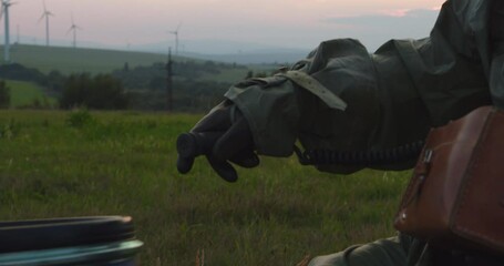A man in a protective suit with a dosimeter inspects a barrel with a warning label reading radioactive.