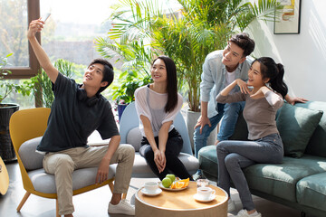 Happy young friends taking selfie at home