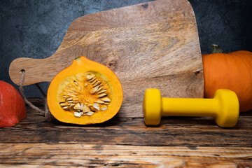 Hokkaido red kuri squash pumpkin and dumbbell. Healthy fitness lifestyle autumn fall rustic...