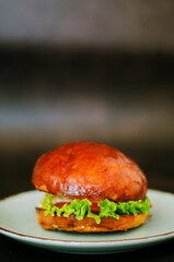 Top view of burger with shrimps, meat patty, salad, tomato against black background. Blue plate. Food lifestyle. Fast food. 