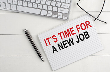 IT'S TIME FOR A NEW JOB text on notebook with keyboard , pen glasses on white wooden background