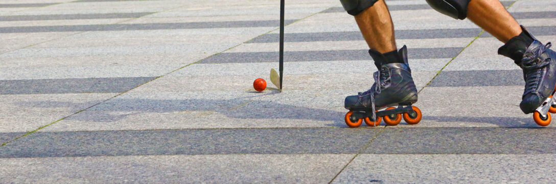Roller in-line hockey outdoor. Closeup of two legs, the stick and the ball.