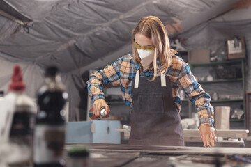 Fototapeta Industrial worker carpenter woman performs painting of wooden detail in workshop obraz
