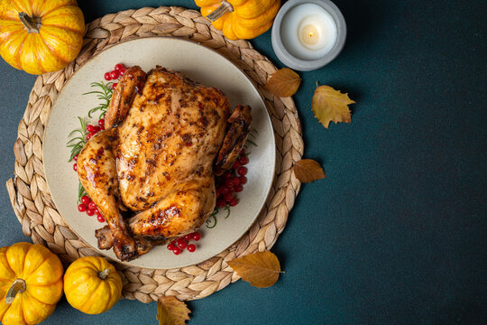 Happy Thanksgiving holiday background. Roasted whole chicken or turkey with autumn vegetables for thanksgiving dinner on dark background