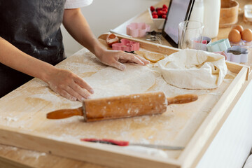 Close up shot of young woman hands kneading dough preparing cakes pizza cookies biscuits in kitchen. Rolling out dough. Flour baking molds on wooden surface.