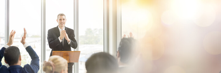 Senior business man talking and clapping hands at podium speaker. Back view of business people...