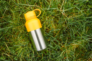 Water bottle. Reusable steel thermo water bottle on green grass. Steel thermo water bottle 