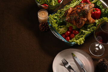 Above view of winter holiday table served, decorated with candles, roast turkey red wine on brown background