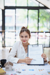 Obraz premium Portrait of a beautiful bank young woman sign credit department of signing approval for a home loan
