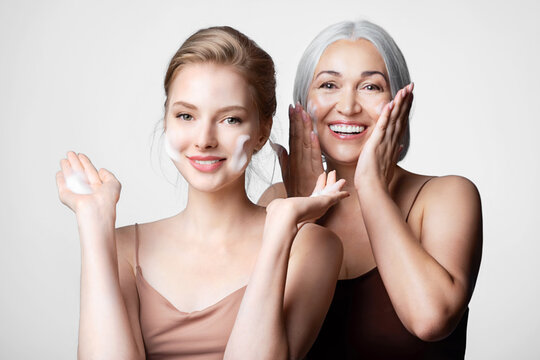 Happy mother and daughter of different ages take care of their skin   washing faces by cleansing cosmetics product. Skincare routine