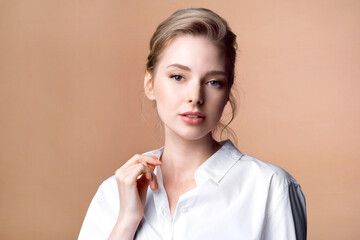 Young blond woman in a white blouse with natural makeup and glowing clear skin