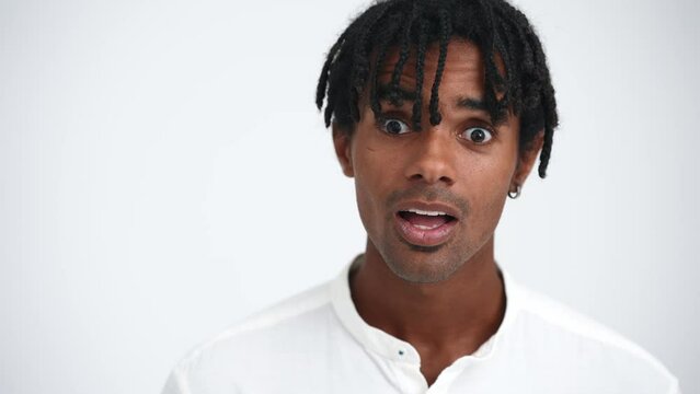 Face of surprised African man with dreadlocks looking at camera in the white studio