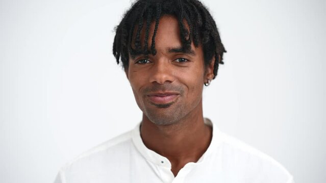 Face of pretty African man with dreadlocks talking at the camera in the white studio