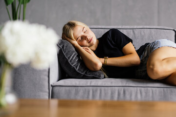 Obraz premium Young attractive woman sleeping on the couch in the living room