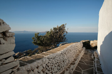 View of a traditional alley next to the Monastery Paleokastro and the Aegean Sea in the background...