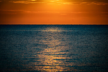 A beautiful bright orange sunset at dusk over a calm sea surface. Beautiful shots of nature.